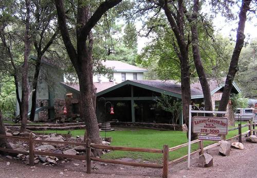 A rustic lodge surrounded by trees, featuring a green lawn and a sign for "Raney Canyon Inn."