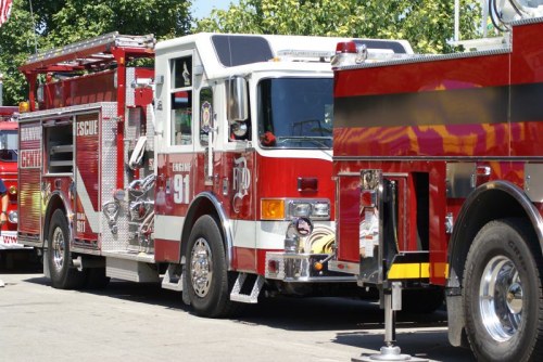 A row of red fire trucks parked, showcasing their shiny exteriors and emergency equipment.