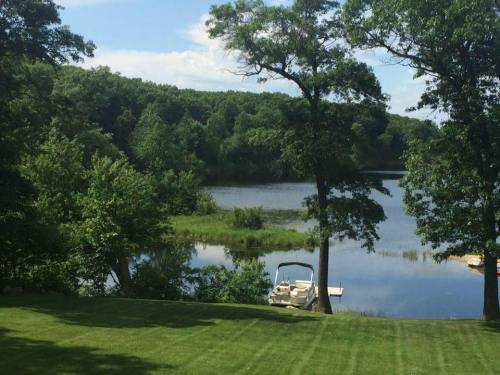 A serene lakeside view with lush greenery, a boat docked, and clear blue skies reflecting on the water.