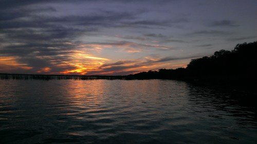 A serene sunset over a calm lake, with colorful clouds reflecting on the water's surface.