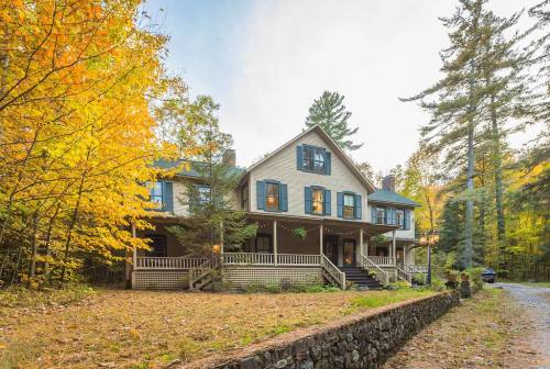 A charming two-story house surrounded by autumn trees and a gravel path, showcasing vibrant fall colors.