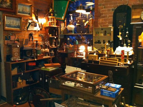 A cozy antique shop filled with various vintage items, including lamps, clocks, and wooden furniture.