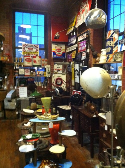 A vintage shop filled with eclectic decor, including signs, furniture, and various antique items on display.