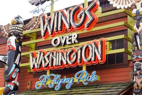Colorful sign for "Wings Over Washington" featuring vibrant lettering and totem pole decorations.