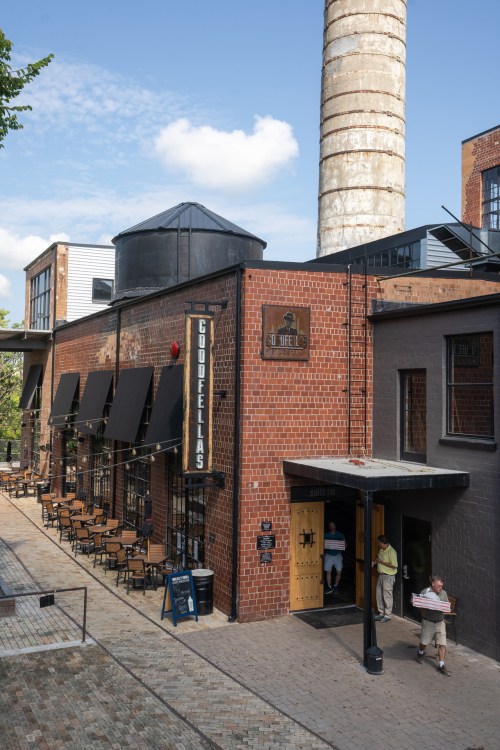 A brick building with outdoor seating, featuring a sign for "Gouffélias" and a tall chimney in the background.