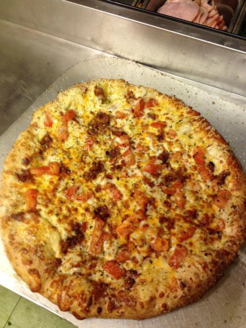 A freshly baked pizza topped with cheese, diced tomatoes, and herbs on a silver tray.