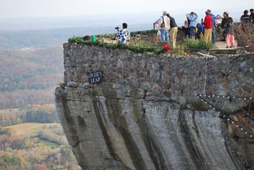 A scenic overlook with visitors at Lovers Leap, featuring a rocky cliff and a panoramic view of the landscape below.