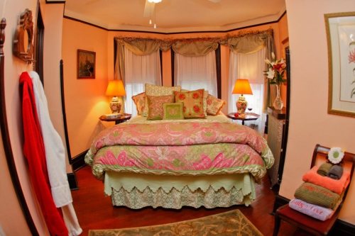 Cozy bedroom with a large bed adorned in floral bedding, warm lamps, and soft lighting, creating a welcoming atmosphere.