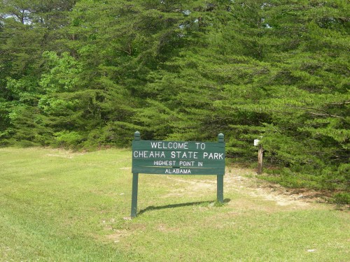 Sign welcoming visitors to Cheaha State Park, the highest point in Alabama, surrounded by lush greenery.