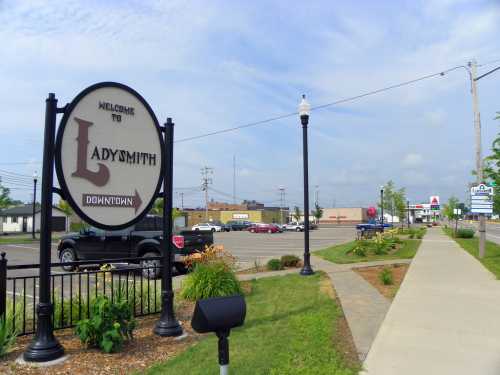 Welcome sign for Ladysmith, with a view of a street and businesses in the background on a clear day.