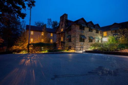A stone building illuminated at dusk, with warm lights glowing from the windows and a serene outdoor setting.