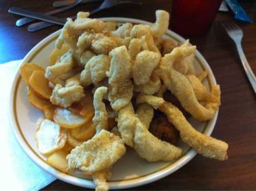 A plate of crispy fried food, featuring a pile of fried fish or chicken strips alongside potato slices.