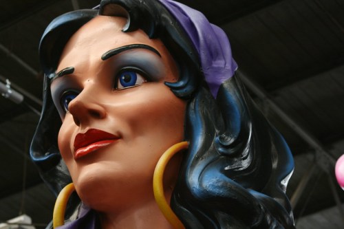 A large, colorful statue of a woman with dark hair, blue eyes, and yellow hoop earrings, set against a dark background.