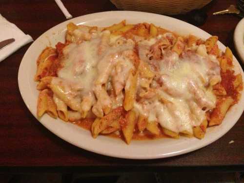 A plate of baked penne pasta topped with marinara sauce and melted cheese.