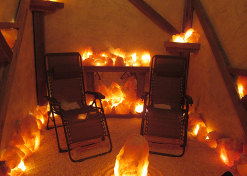 A cozy room with two reclining chairs surrounded by glowing salt crystals, creating a warm, relaxing atmosphere.