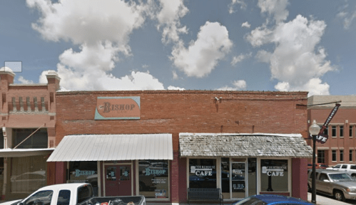 A brick building with a sign reading "Bishop" and a café, under a partly cloudy sky.
