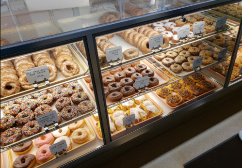 A display case filled with various donuts, including glazed, chocolate, and sprinkled varieties.