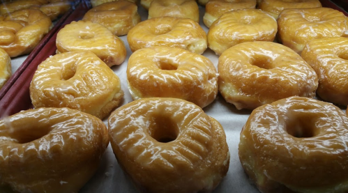 A display of glazed donuts arranged neatly on a tray, showcasing their shiny, golden-brown surface.