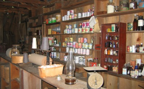 A rustic interior with wooden shelves filled with vintage cans, bottles, and various old tools and equipment.