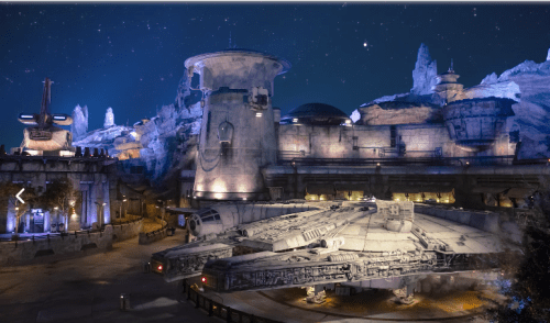 A futuristic spaceship parked in a detailed, illuminated sci-fi landscape under a starry sky.