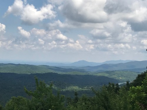 A scenic view of rolling green mountains under a partly cloudy sky.