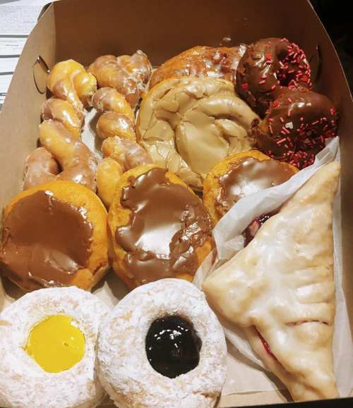 A box filled with various donuts, including glazed, chocolate-covered, and filled pastries, all arranged neatly.