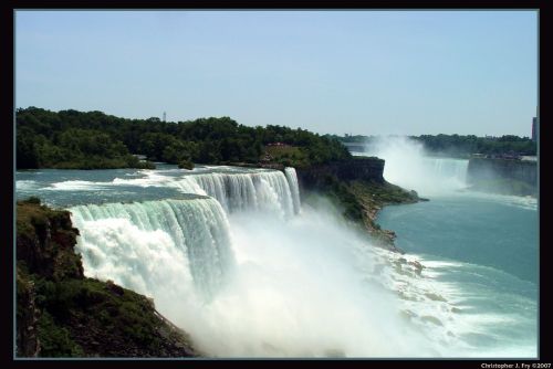 A scenic view of Niagara Falls, showcasing cascading water and mist against a lush green backdrop.
