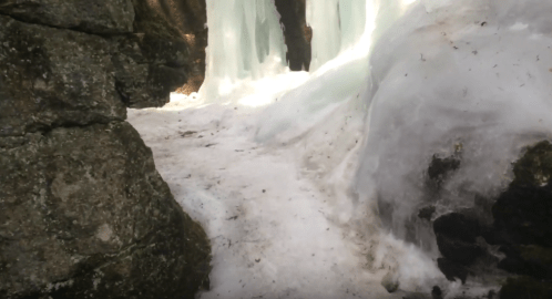 A narrow path between icy rocks, with snow and ice formations on either side.