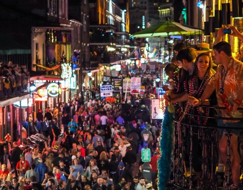 A vibrant street scene during a festival, with crowds celebrating and colorful lights illuminating the buildings.