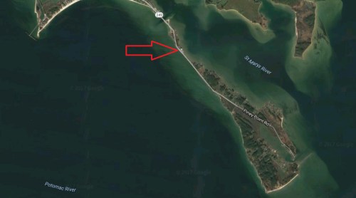Aerial view of a river delta with a marked arrow indicating a specific point along the shoreline.