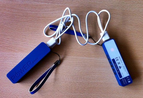 Two blue power banks with white charging cables, placed on a wooden surface.