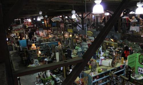 A spacious antique store filled with various vintage items, furniture, and decor under warm lighting.