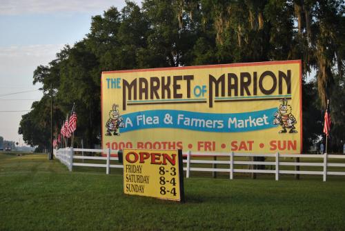 Sign for The Market of Marion, a flea and farmers market, with operating hours and colorful graphics.