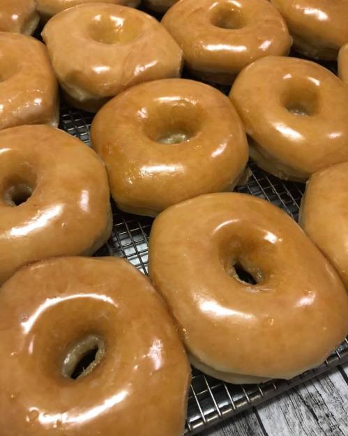 A close-up of freshly glazed donuts arranged on a cooling rack.