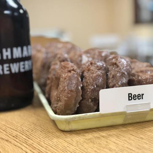 A tray of beer-flavored donuts next to a bottle labeled "Brewery."