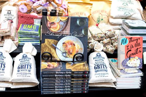 A display of cookbooks, including "Shrimp and Grits" and "101 Things to Do with Grits," alongside bags of grits.