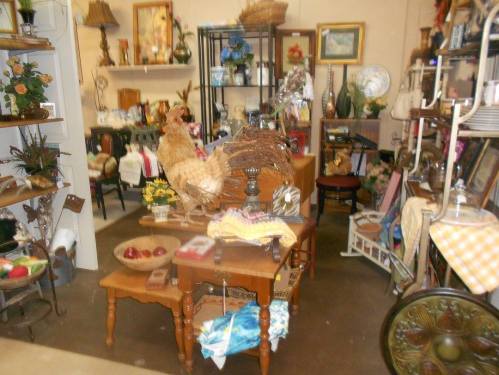 A cozy antique shop filled with various vintage items, including furniture, decor, and floral arrangements.