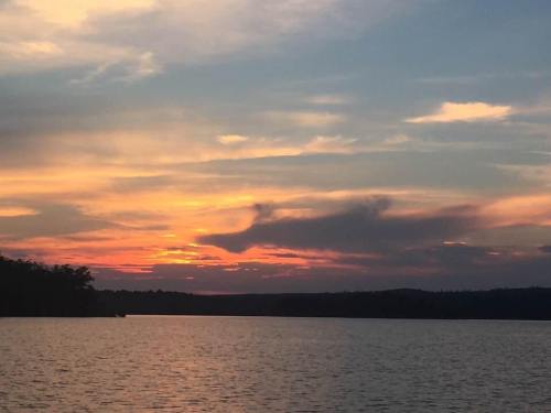 A serene sunset over a calm lake, with vibrant orange and pink hues reflecting on the water.