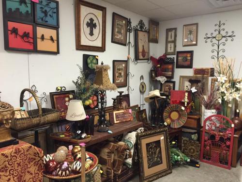A cozy display of various decorative items, including framed art, lamps, and wall decor in a shop setting.