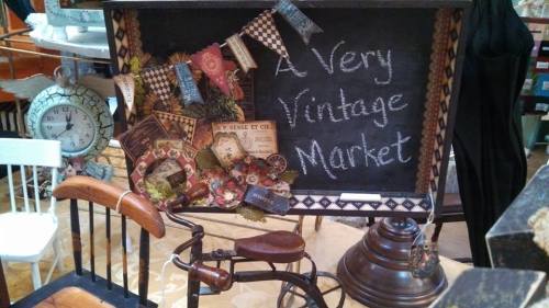 A chalkboard sign reading "A Very Vintage Market," decorated with vintage items and a small bicycle.
