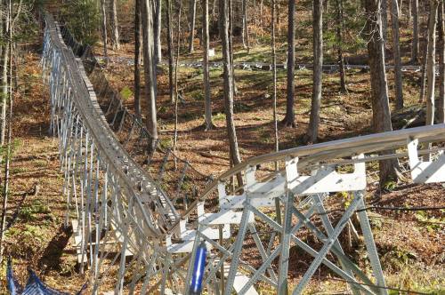 A winding roller coaster track through a wooded area with autumn foliage.