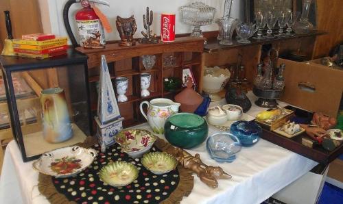 A display of various antiques and collectibles, including vases, dishes, and decorative items on a table.