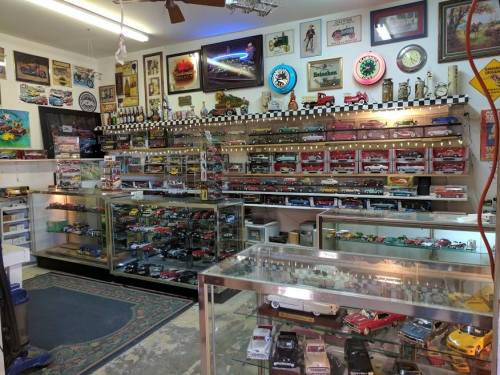 A display room filled with model cars, memorabilia, and vintage signs, showcasing a variety of collectibles.