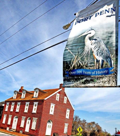 A historic red brick building with a sign featuring a heron and text about Dory Penn's 300 years of history.