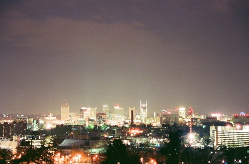 A nighttime cityscape featuring illuminated buildings and a skyline against a dark sky.