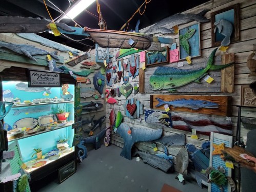 A colorful display of wooden fish art and crafts in a rustic shop, featuring various marine-themed decorations.