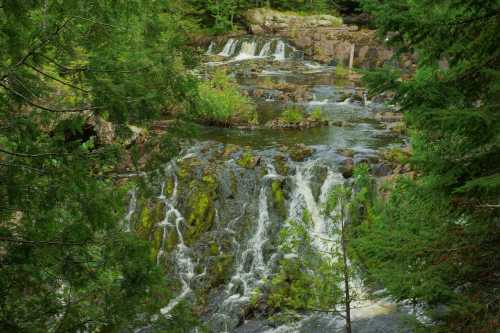 A serene waterfall cascading over rocks, surrounded by lush green trees and foliage.