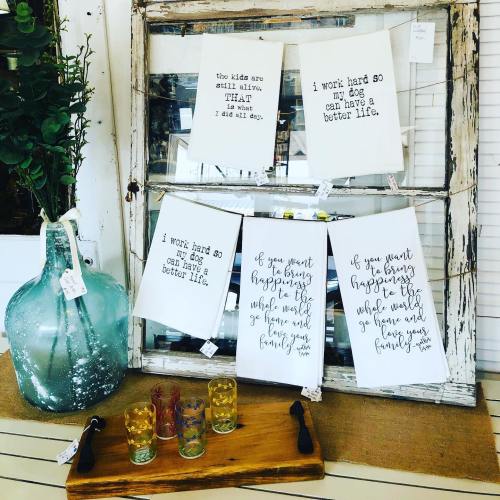 A rustic display featuring motivational prints and colorful shot glasses on a wooden table.