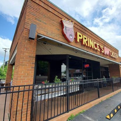 Exterior of Prince's Hot Chicken restaurant, featuring a brick facade and a sign with a cartoon crown and face.