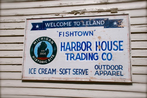 Sign for Harbor House Trading Co. in Leland, Michigan, featuring ice cream, soft serve, and outdoor apparel.